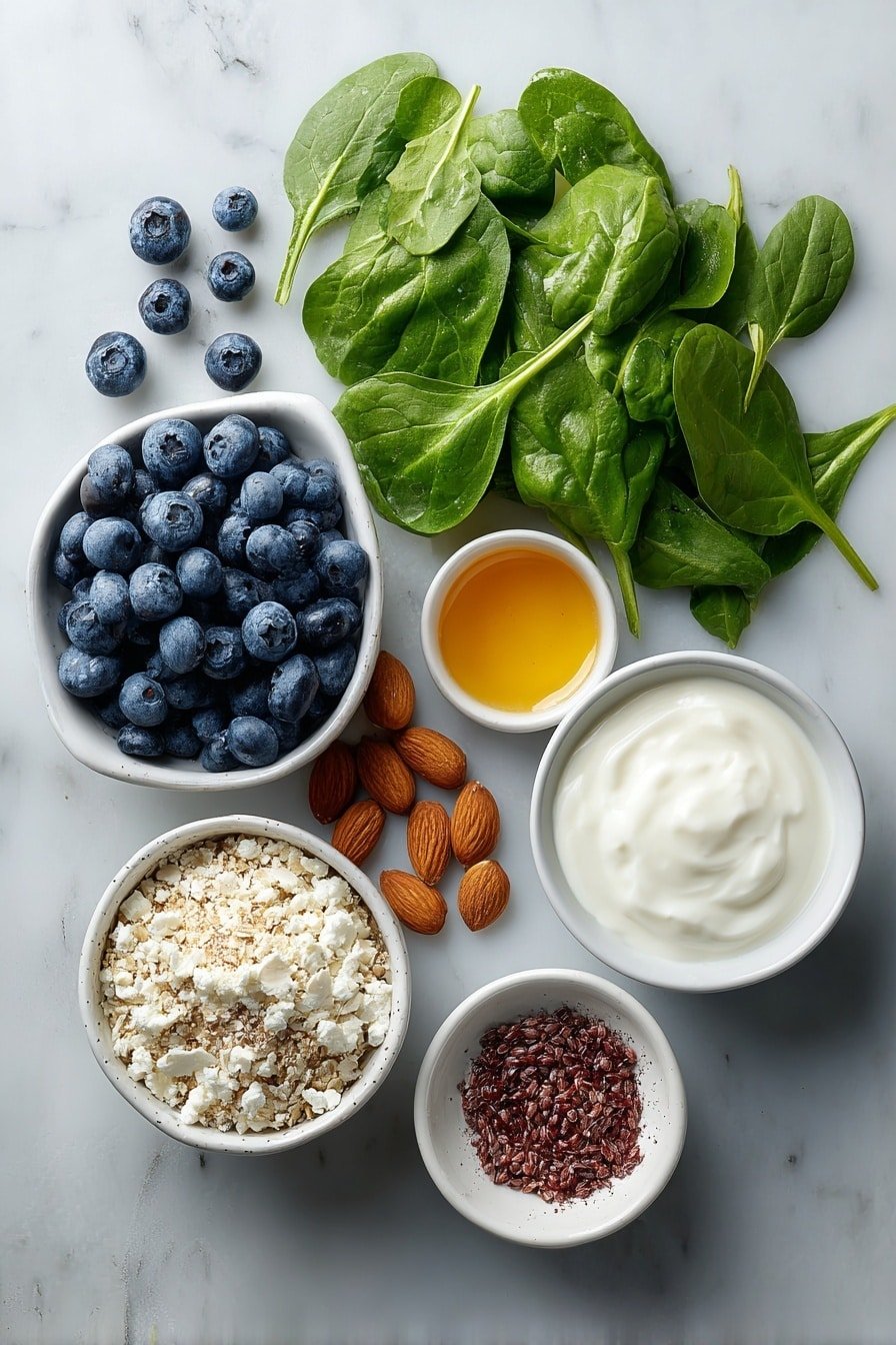 Flat lay of fresh spinach leaves arranged beside a small mound of vibrant blueberries, a small white ceramic bowl filled with smooth dairy-free yogurt, a small white bowl holding rich golden agave syrup, a small white bowl containing light brown flaxseed meal, a small white bowl with creamy almond milk, and a tiny white bowl with a sprinkle of warm ground cinnamon, whole uncracked brown almond shells artistically placed for natural contrast, all ingredients placed symmetrically on a clean white marble surface, soft natural light, photo taken with an iPhone, professional food photography style, fresh ingredients, white ceramic bowls, no bottles, no duplicates, no utensils, no packaging --ar 2:3 --v 7 --p m7354639359234015250 — Healthy Spinach Blueberry Smoothie, nutritious green smoothie, easy healthy smoothie, blueberry spinach smoothie recipe, quick breakfast smoothie